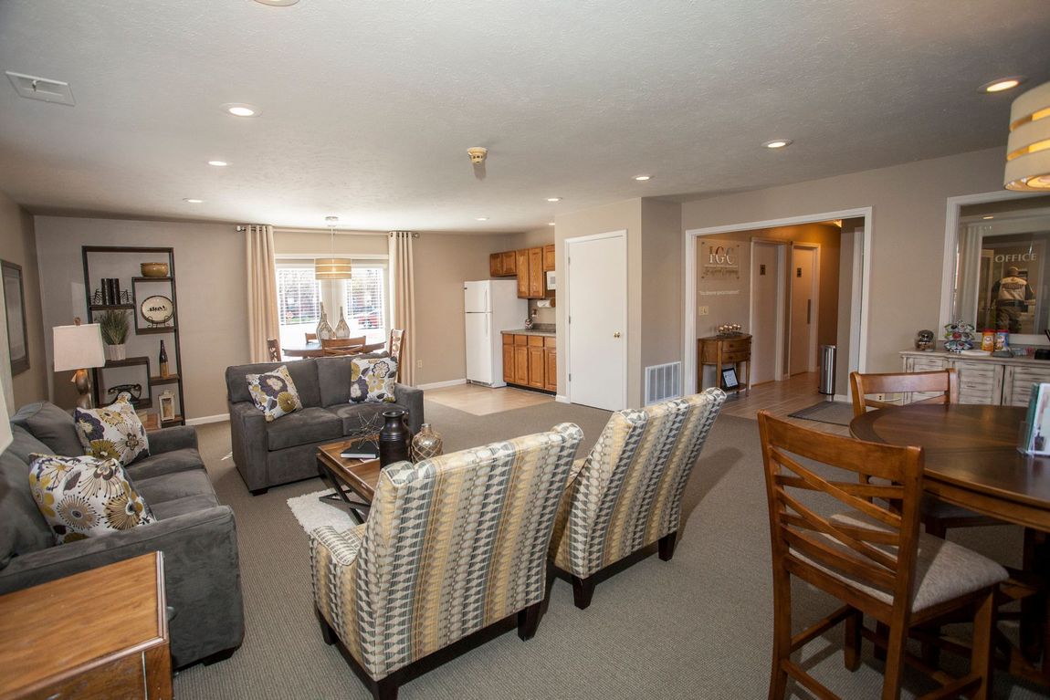 Living room with two sofas, two patterned chairs, small kitchen, dining table.