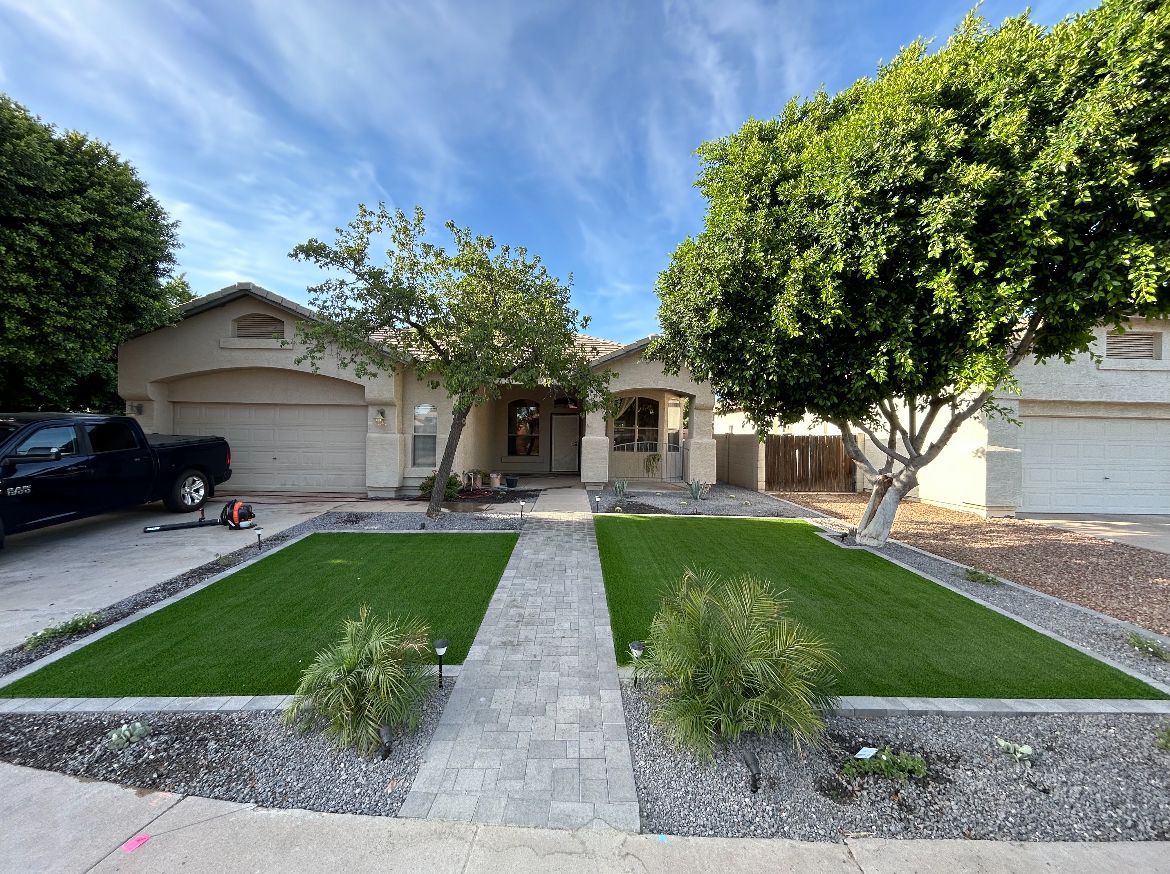 Suburban house with a double garage, green lawn, and a concrete walkway bordered by trees