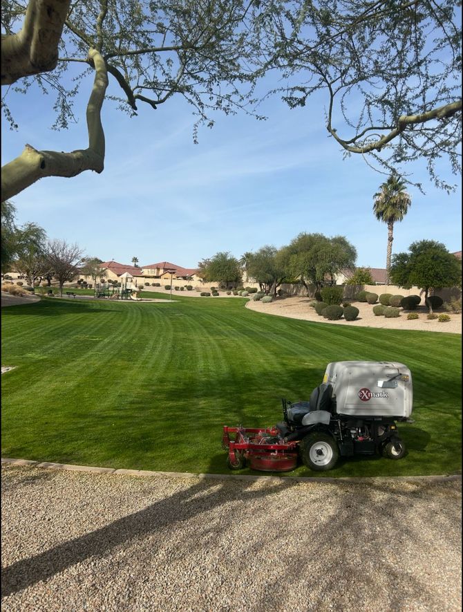 Golf course groundskeeper mower on green fairway under a blue sky