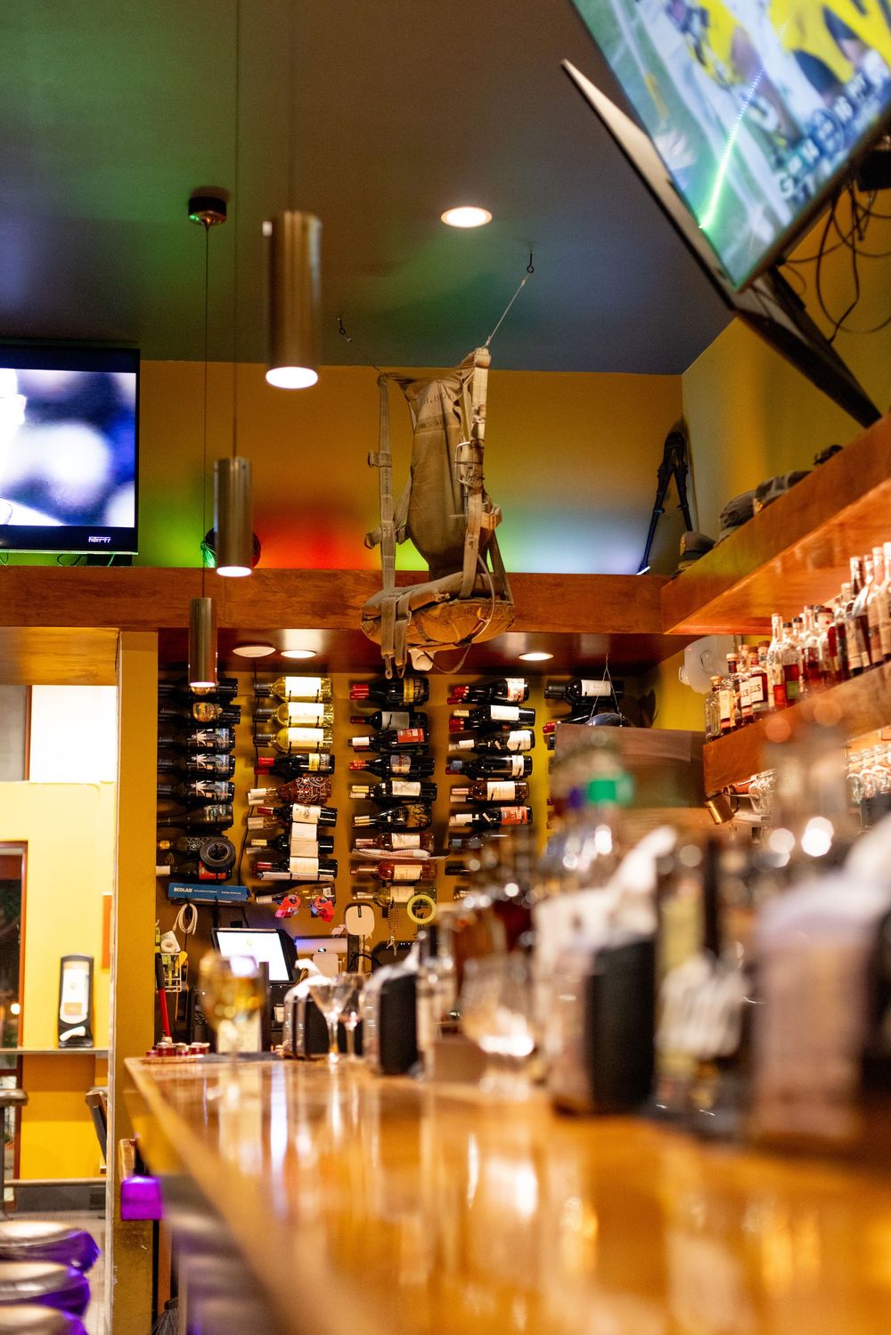 Interior view of The General Historic Bar in Marina, California, featuring the wooden bar, wine display, military decor, and TVs.
