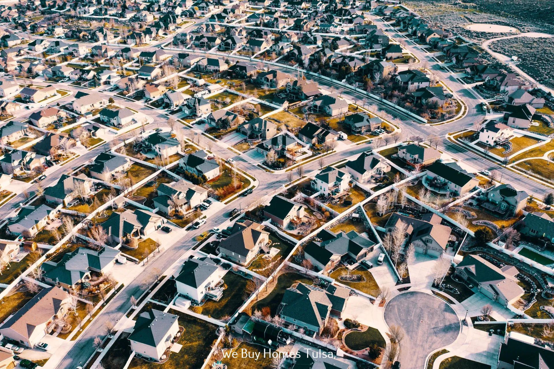 Aerial view of a dense suburban neighborhood with houses, streets, and cul-de-sacs under a twilight sky.