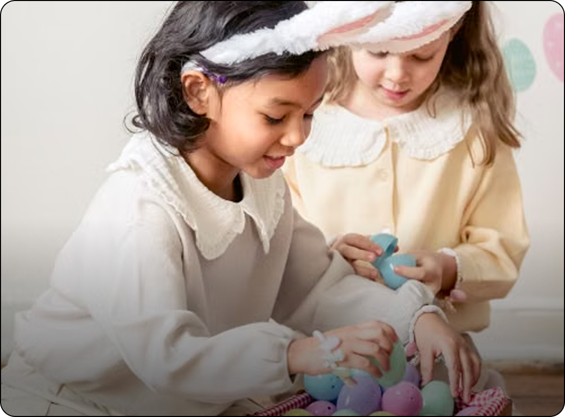 Two children in pastel costumes playing with colorful eggs at a table