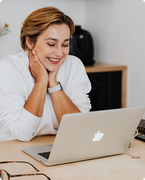 Smiling person working on a laptop at a desk in a bright office