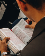 Person reading a book with highlighted text in a seated indoor setting