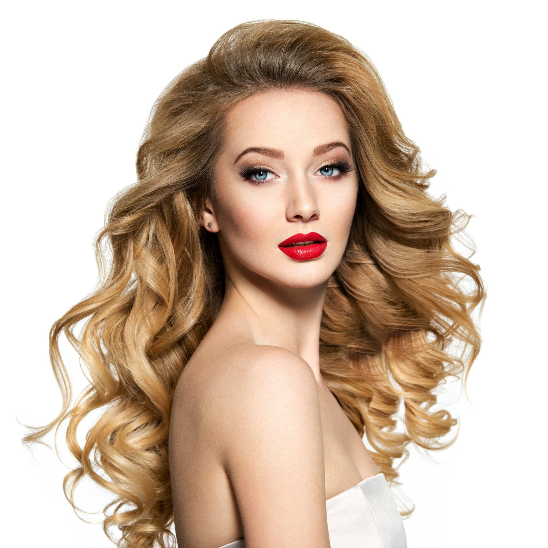 A woman with long curly hair and red lips is wearing a white dress.