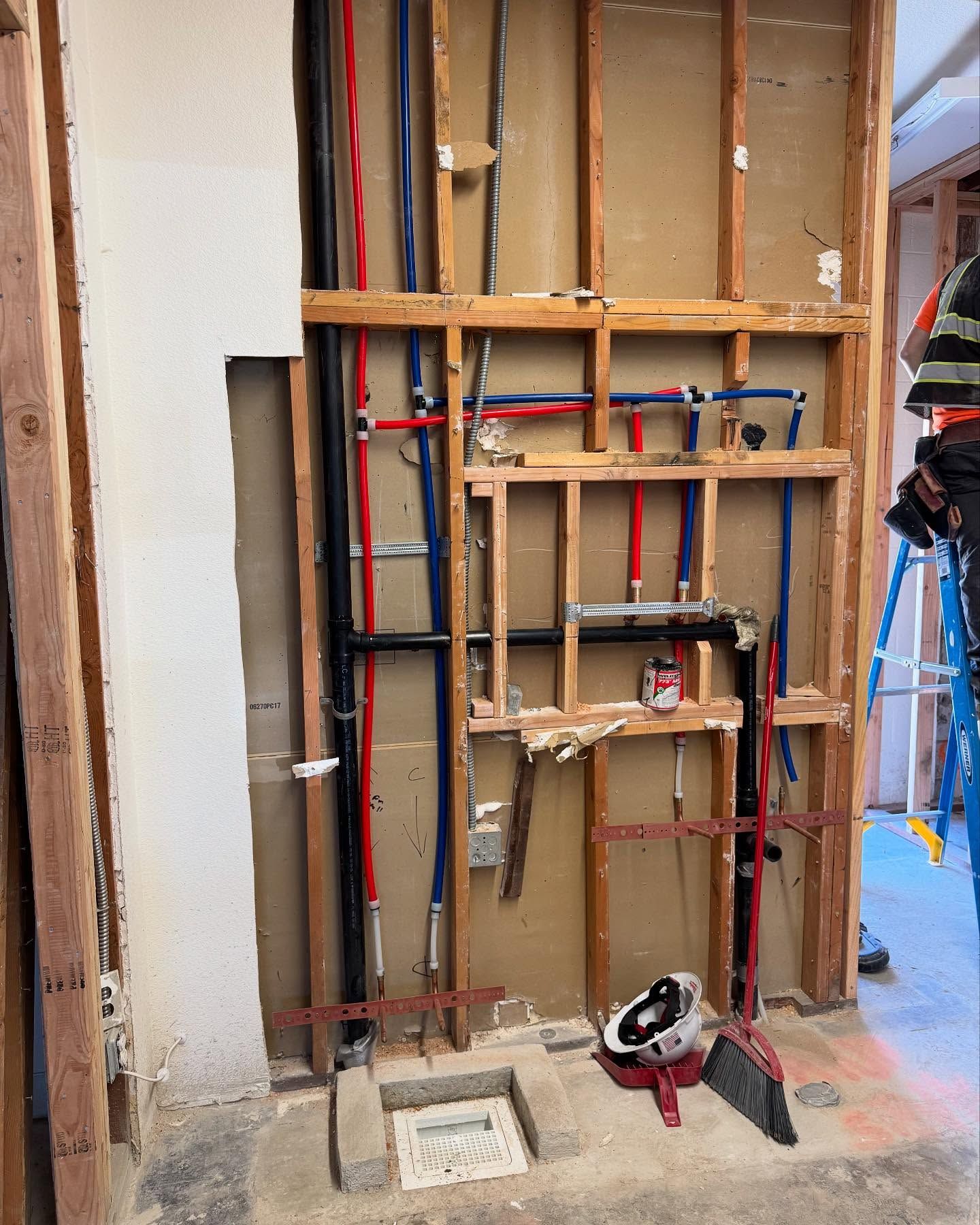 Interior wall with exposed plumbing and framing during renovation.