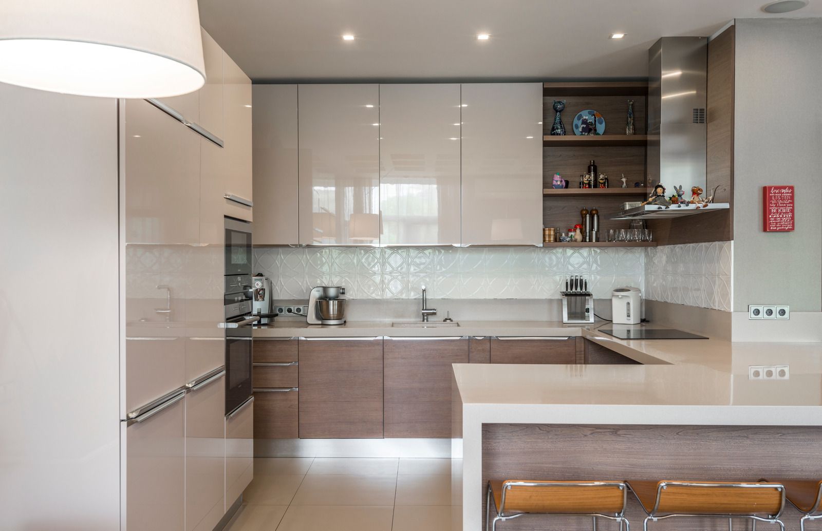 Modern beige kitchen with glossy cabinets, island counter, and tiled backsplash