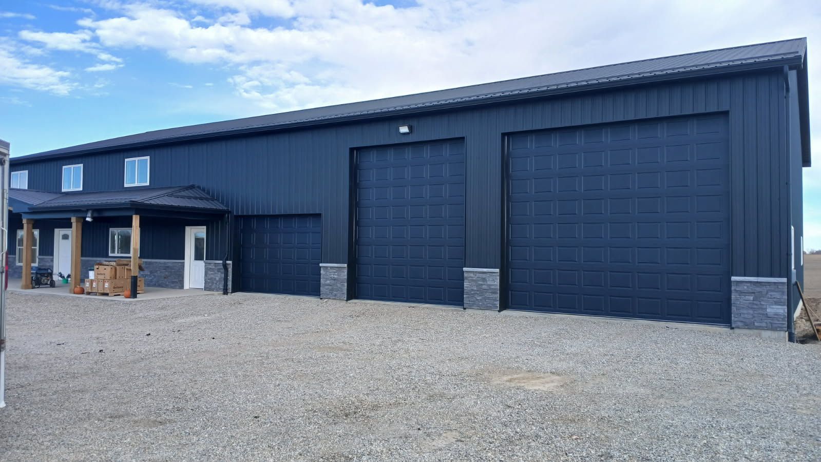 Modern industrial building entrance with two gray garage doors and white corrugated walls