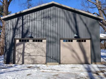 Gray garage door on a suburban house exterior with stone trim and driveway.