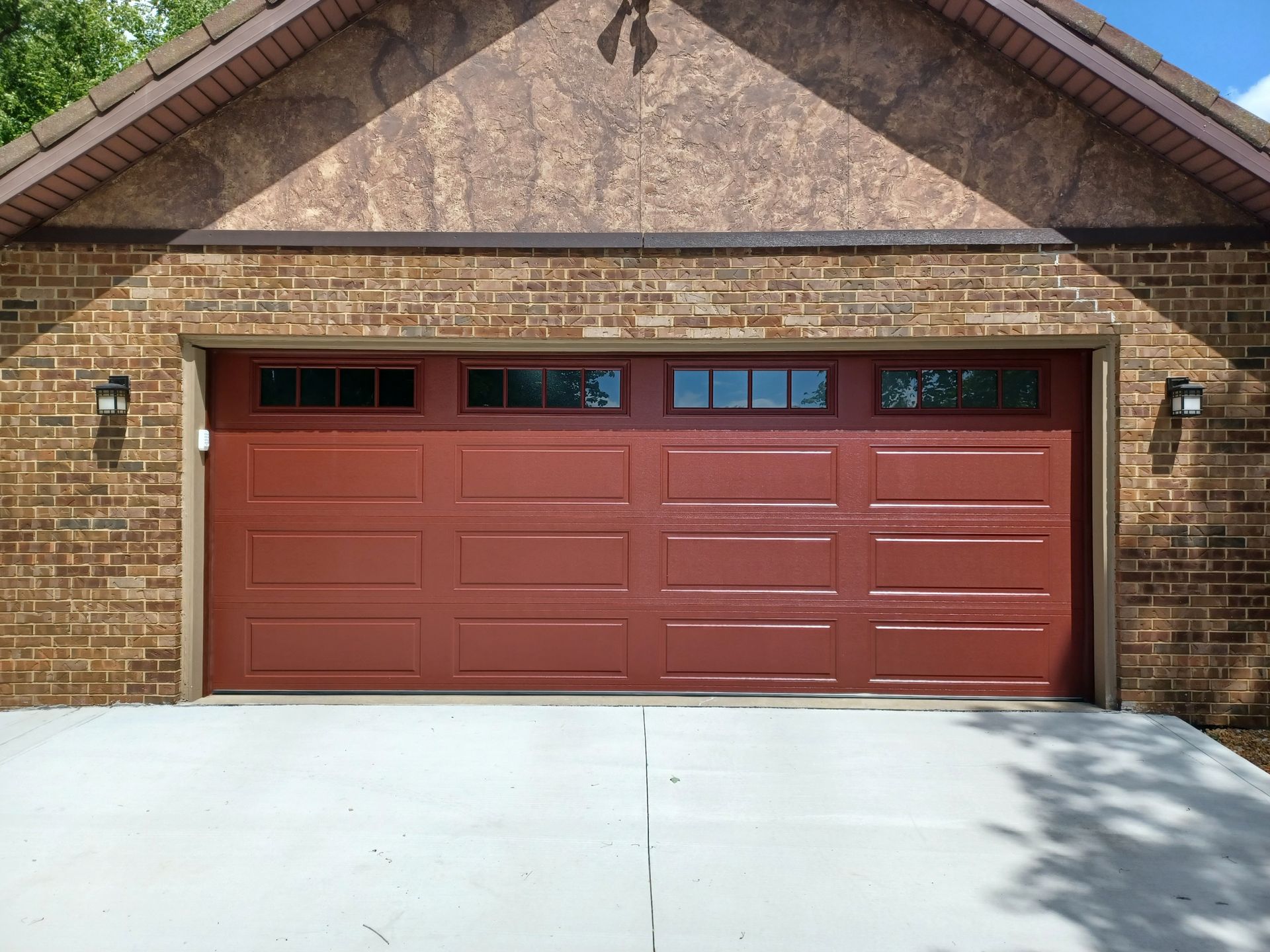 Empty garage with a partially open blue sectional door and concrete floor.