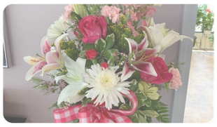Bouquet of pink, white, and green flowers tied with a pink checkered ribbon