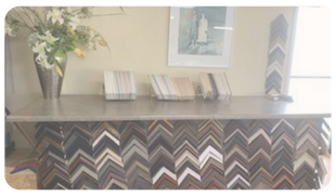 Decorative console table with chevron-pattern front, white books, framed art, and a vase of flowers