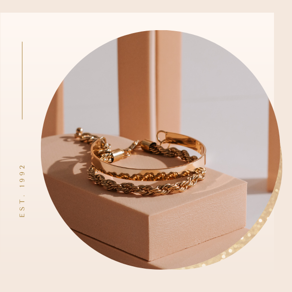 Gold chain bracelets on a blush jewelry box in warm sunlight