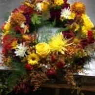 Colorful floral wreath with yellow, red, and white flowers on a stand