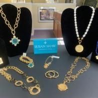Jewelry display with gold and turquoise necklaces, bracelets, and rings on black stands