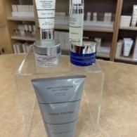 Skincare products displayed on a clear acrylic shelf in a store aisle.