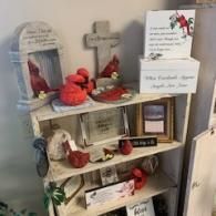 Decorated shelf with red apples, a cross, and handwritten signs in a cozy home display