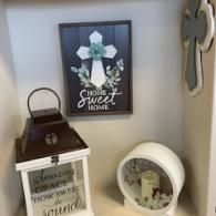 Wall decor with a white flower sign, lantern, and framed “Home Sweet Home” print on a shelf