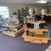 Retail display of jewelry and accessories on wooden shelves in a store with purple carpet