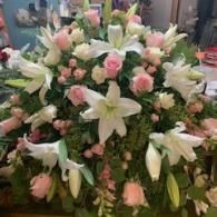Large white and pink floral arrangement with lilies and roses in a vase