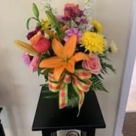 Colorful bouquet with orange lilies and yellow flowers on a small black table