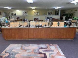 Jewelry store interior with glass display cases, wooden counter, and patterned rug on carpeted floor