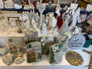Gift shop display of angel figurines, memorial plaques, and sympathy keepsakes in white and pastel tones