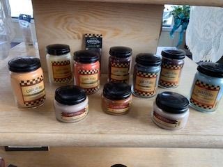 Assorted jars of jam and preserves arranged on a wooden shelf in a market display