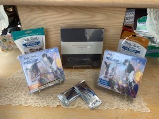 Gift basket with two boxed items, two pouches, and a small silver box on a lace-covered table.