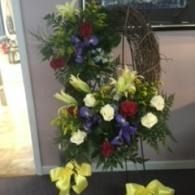 Floral standing arrangement with yellow, white, purple, and red flowers in a hallway