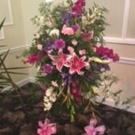 Pink and purple floral arrangement with lilies and greenery in a vase indoors
