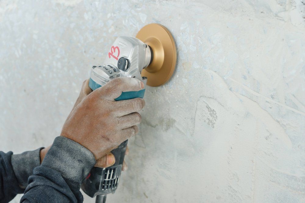 Worker Grinds The Concrete Wall With Grinding Machine — Concrete Grinding in Bundaberg, QLD