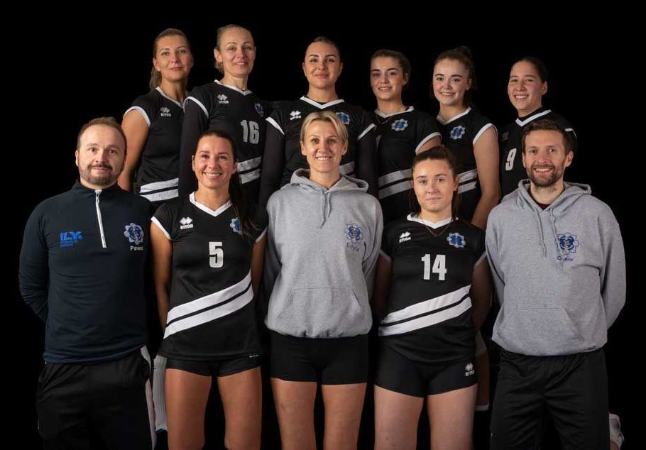 A group of volleyball players are posing for a picture with their coaches.