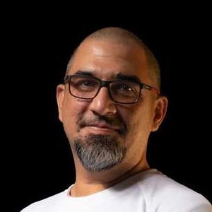 A man with a beard and glasses is wearing a white shirt.