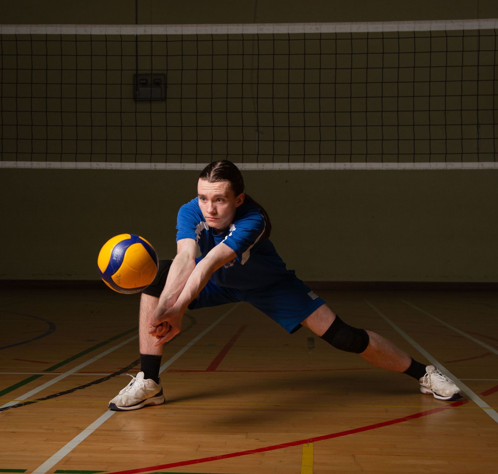 A man in a blue shirt is playing volleyball on a court.