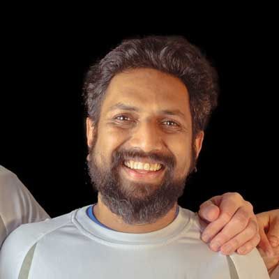 A man with a beard is smiling and holding another man 's arm.
