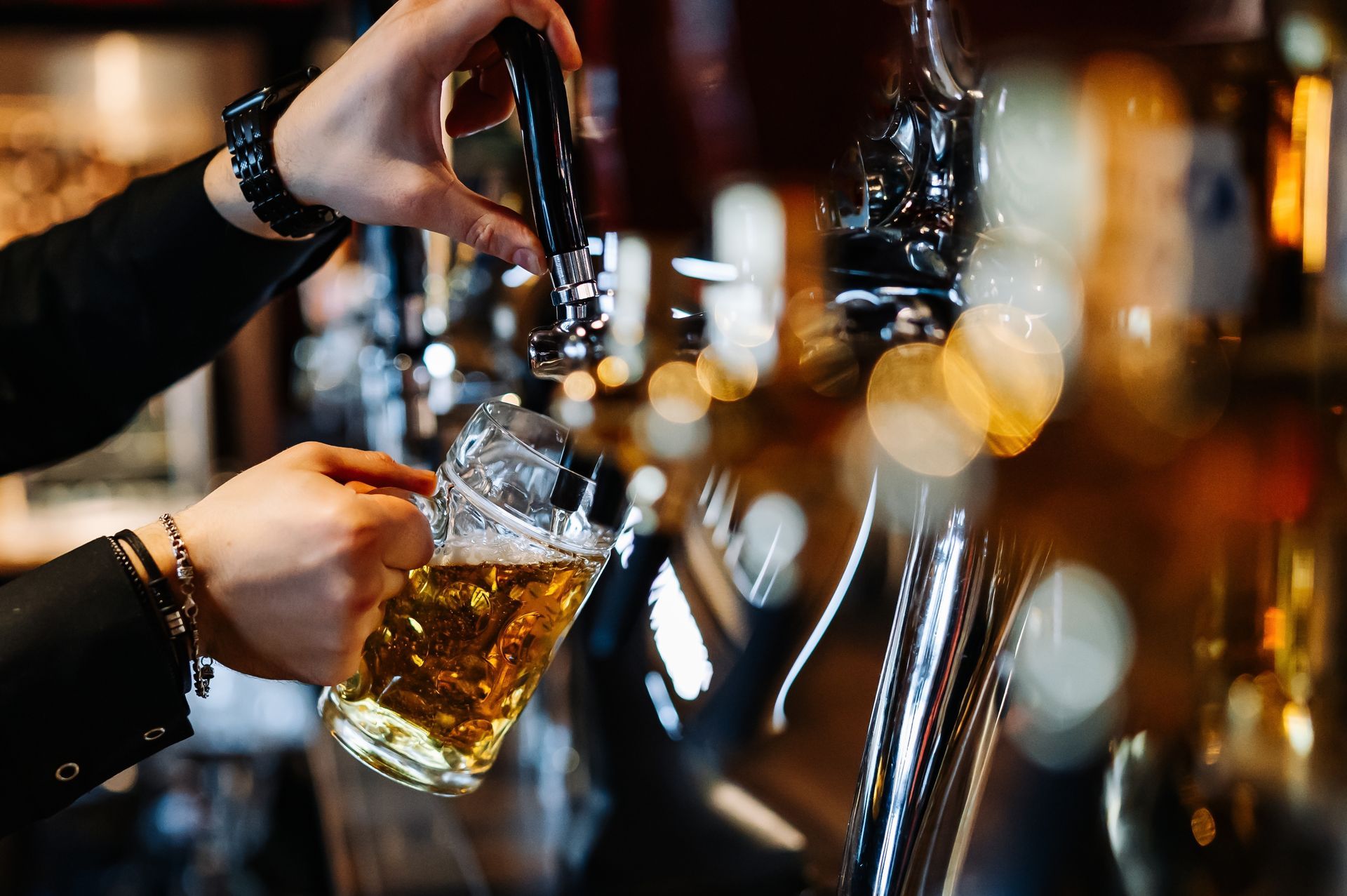Bartender pouring beer into a glass mug at a bar.