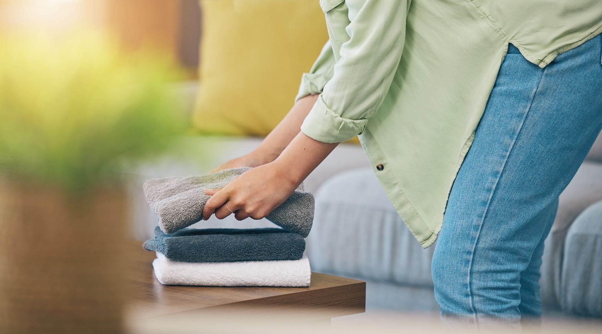 Person folding towels on a table in a bright room