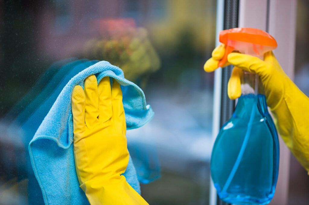 Two cleaning workers in a bright office, with a cleaning cart. One wears a blue headscarf.