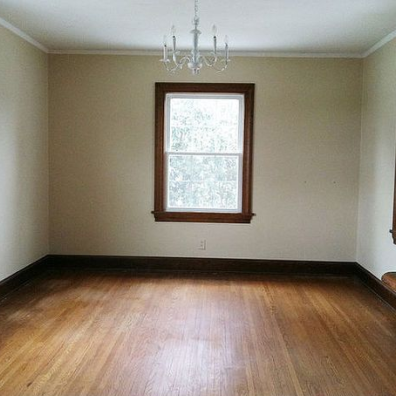 Empty beige room with hardwood floors, a centered window, and a small chandelier overhead