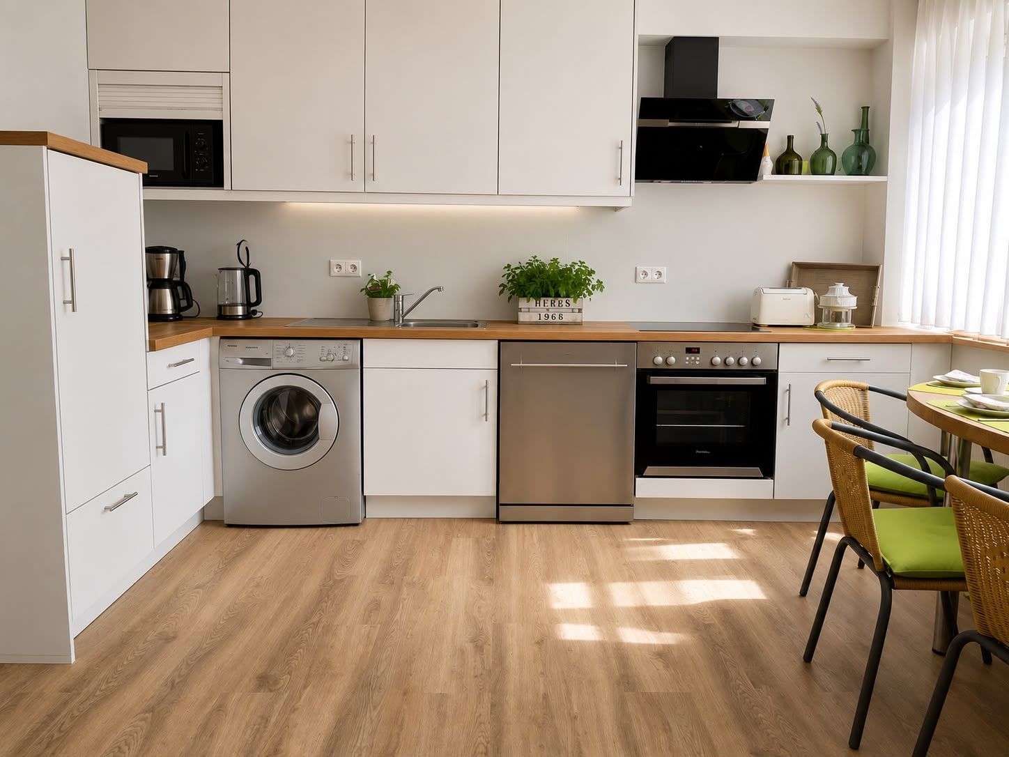 Moderne Küche mit weißen Schränken, Holzboden, Waschmaschine und Esstisch am Fenster