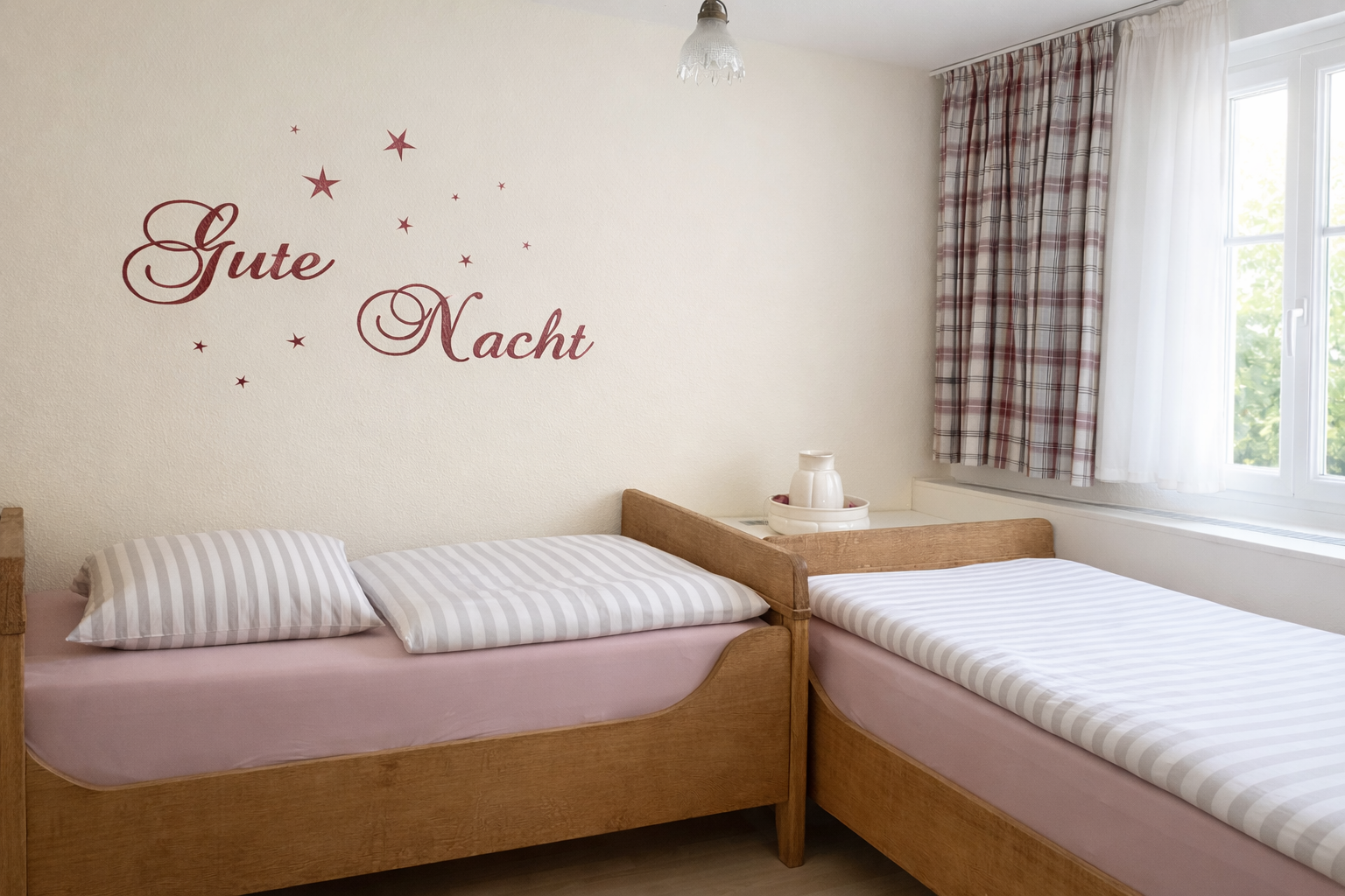 Gemütliches Schlafzimmer mit zwei Einzelbetten, gestreifter Bettwäsche und einem „Gute Nacht“-Wandtattoo