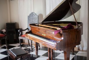 Un pianoforte a coda è appoggiato su un pavimento a scacchi in una stanza.