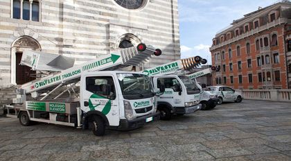 Una fila di camion in movimento è parcheggiata davanti a un edificio.