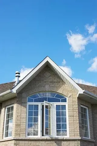 a brick house with a large window and a blue sky in the background .