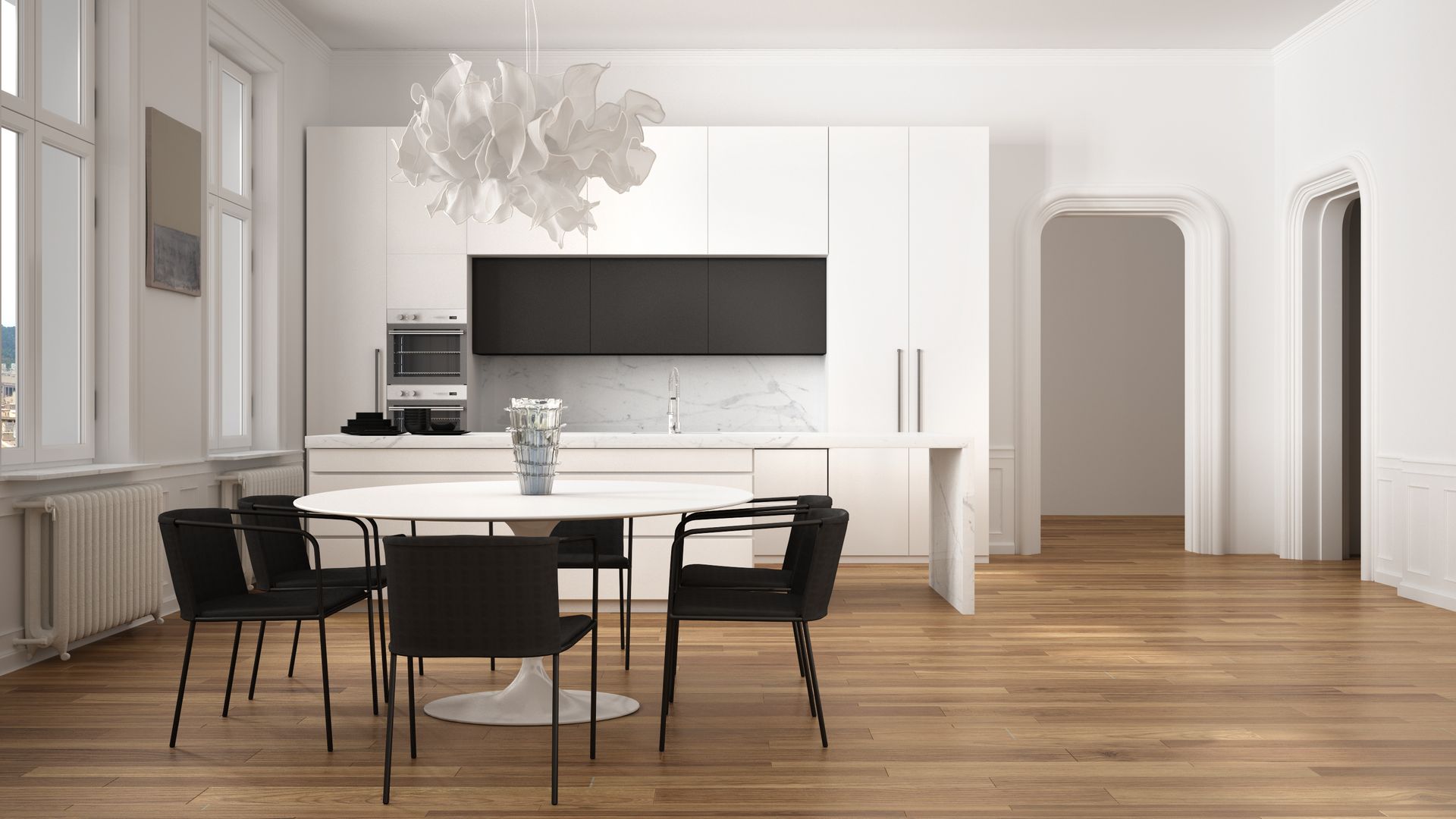 Modern white kitchen with black accents, dining table, chairs, and vinyl floors.
