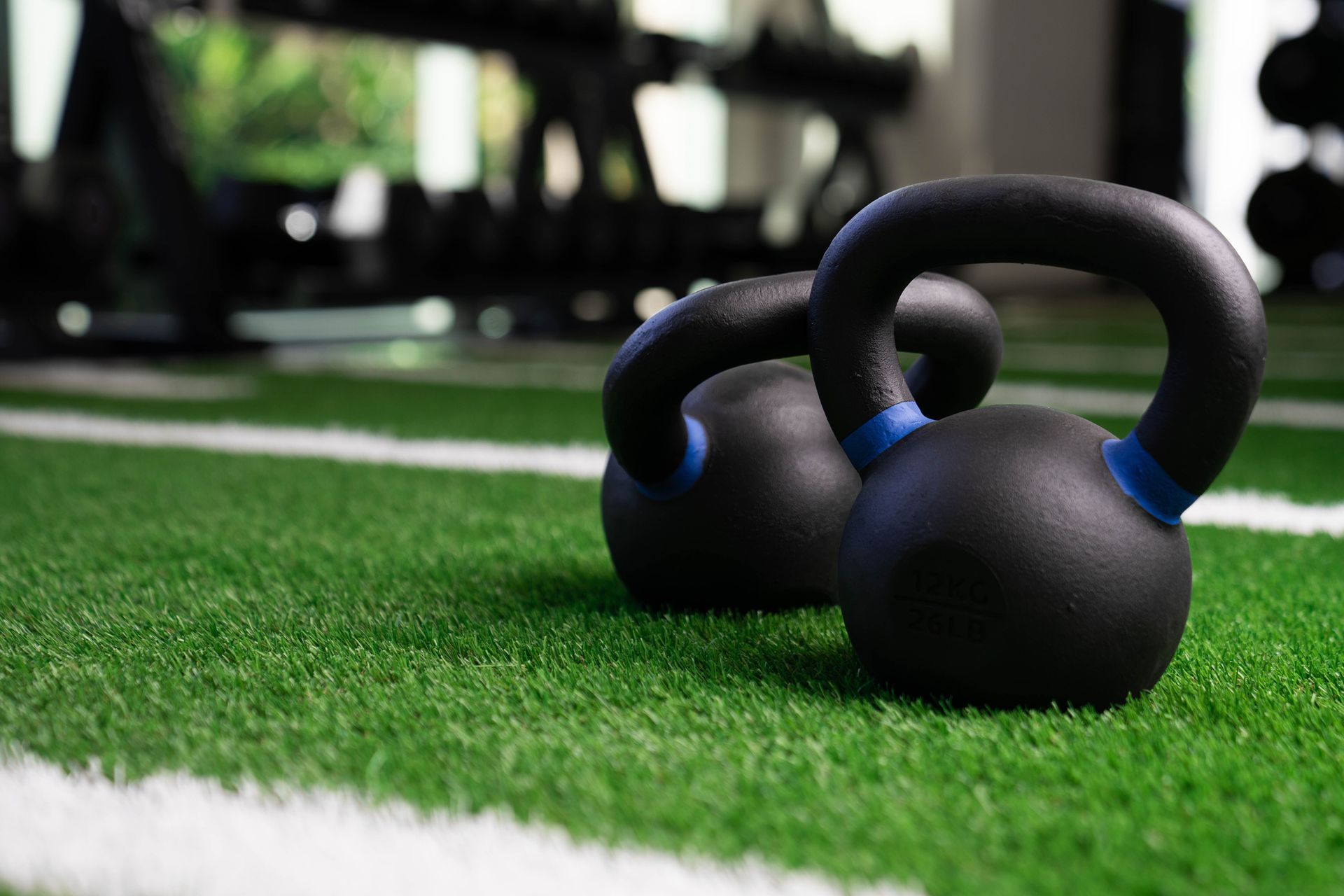 Hand lifting a section of green artificial turf, revealing the black backing.