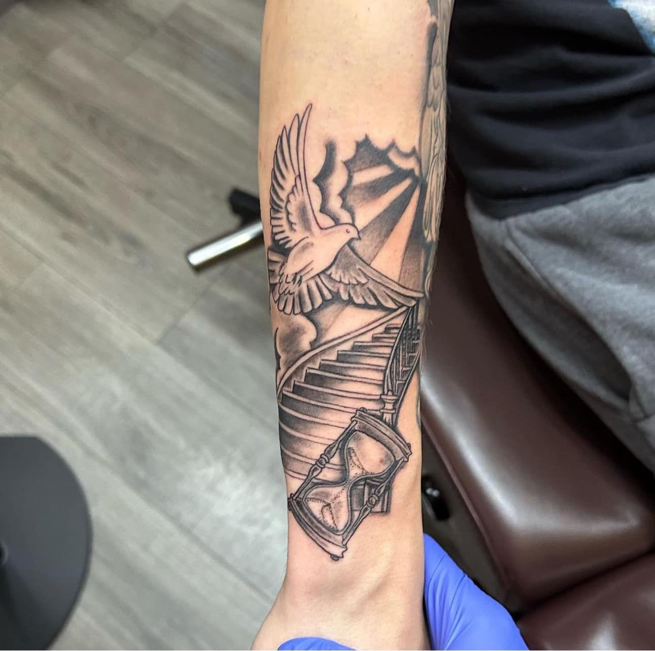 Forearm tattoo of an eagle and winding staircase in black ink on a person’s arm