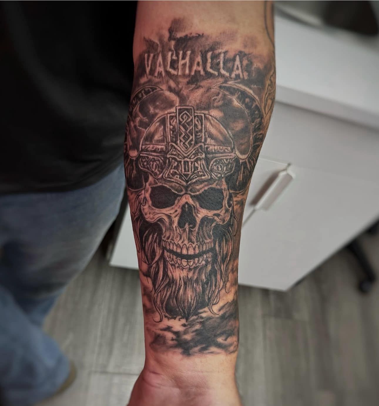 Forearm tattoo of a skull with Valhalla text and dark shaded details