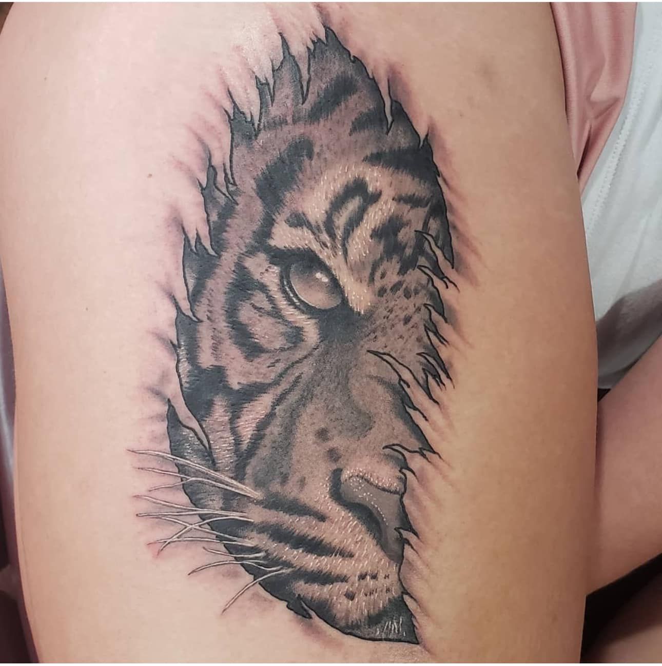 Black-and-gray tiger face tattoo on a person’s upper arm